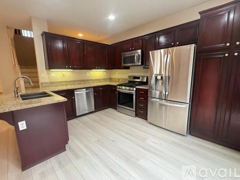 A kitchen with dark wood cabinets and stainless steel appliances.
