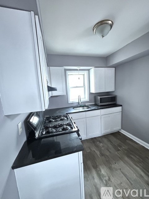 A kitchen with white cabinets and a black countertop.