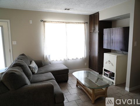 A living room with a grey couch and a glass coffee table.