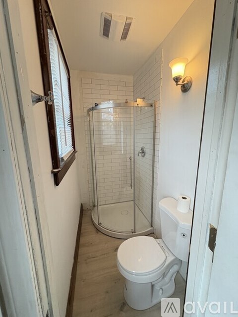 A white toilet in a small bathroom with a glass shower door.