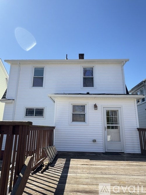 A white house with a wooden deck and a blue sky.