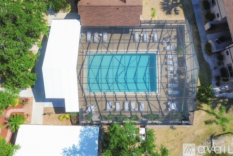 An aerial view of a swimming pool surrounded by trees and buildings.