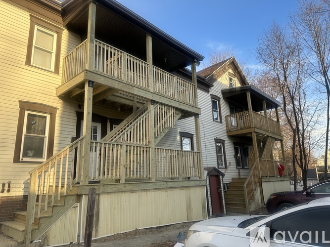 A two-story house with a balcony and a car parked in front.