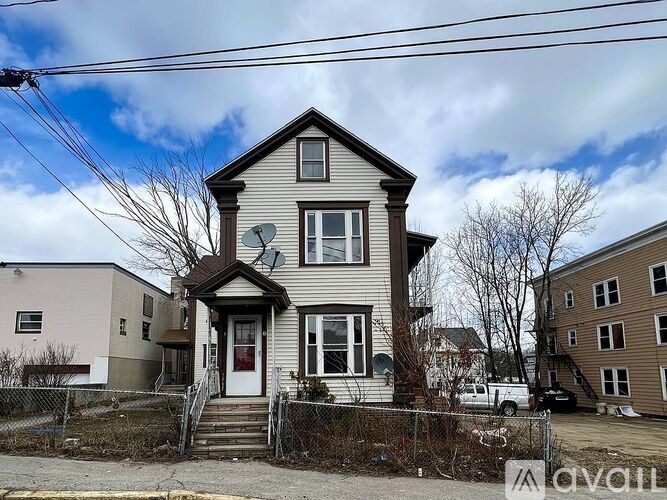 A two-story house with a front porch and a satellite dish on the roof.