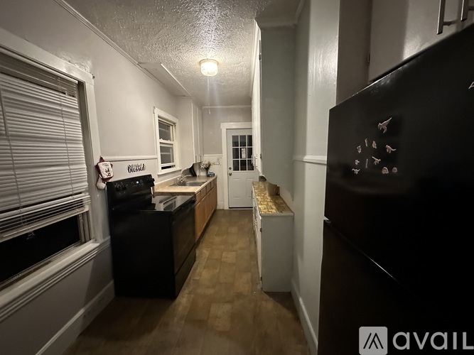 A kitchen with a black fridge and a black stove top oven.