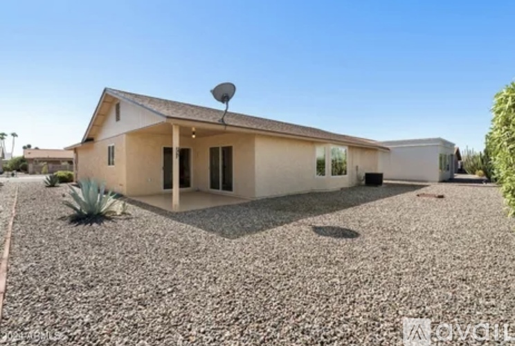A house with a gravel driveway and a satellite dish on the roof.