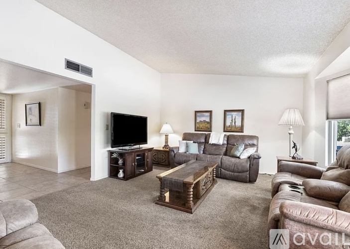 A living room with a grey carpet and furniture.