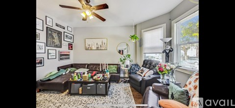 A living room with a brown leather couch and a coffee table with a vase of flowers on it.