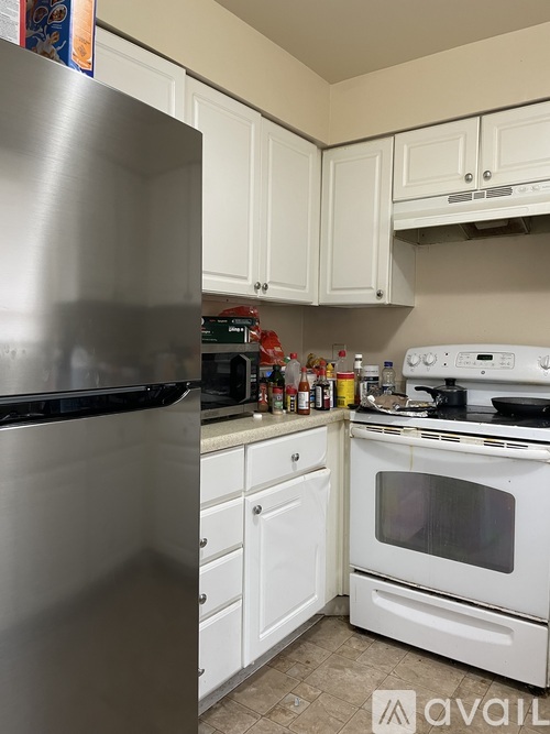 A kitchen with a stainless steel refrigerator and white cabinets.