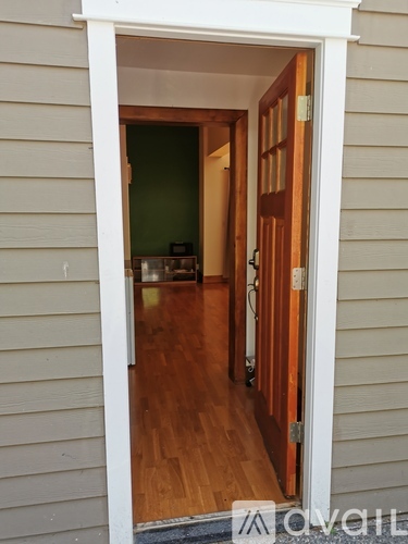 A white doorway opens to a room with wooden floors.