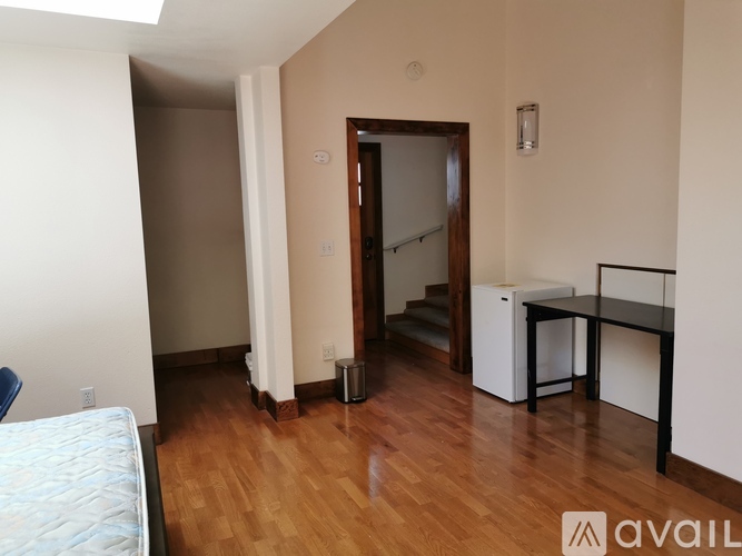 A room with a bed, a desk, and a staircase.