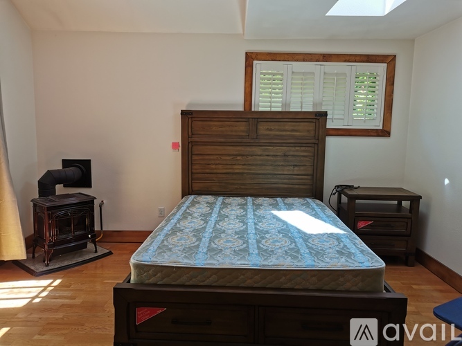A bedroom with a bed, nightstand, and window.