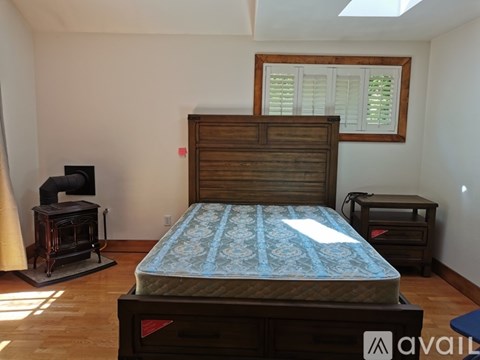 A bedroom with a bed, nightstand, and window.
