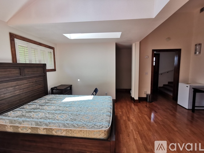 A bedroom with a bed, dresser, and a window with blinds.