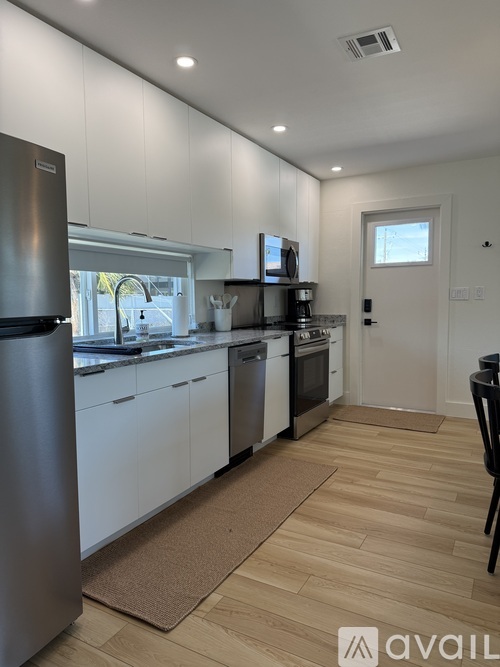 A kitchen with white cabinets and a wooden floor.