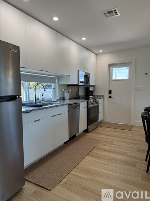 A kitchen with white cabinets and a wooden floor.