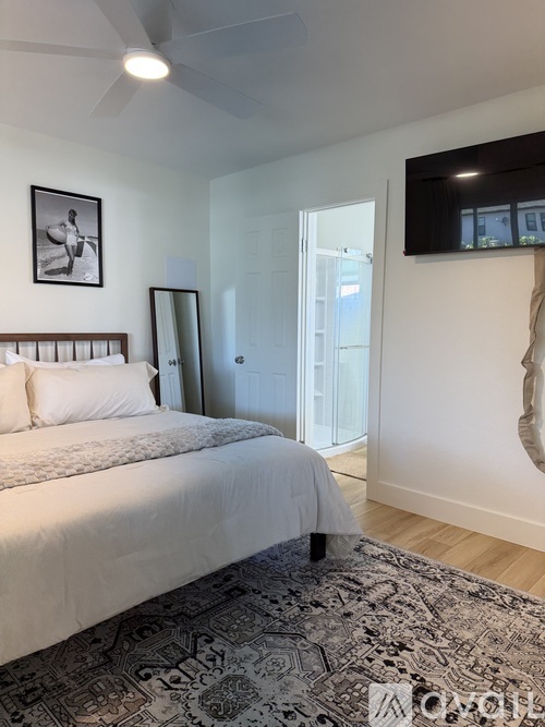 A bedroom with a large bed and a ceiling fan.