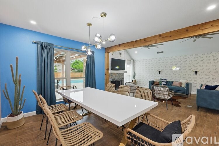 A living room with a white table and chairs, a cactus, and a television.