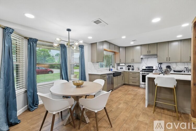 A kitchen with a table and chairs in front of a window with curtains.