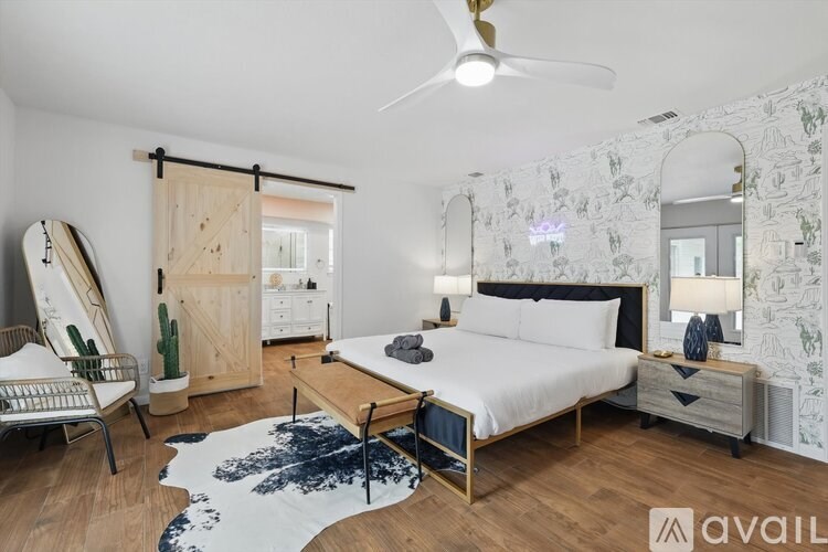 A bedroom with a bed, dresser, and mirror with a white and black patterned wallpaper.