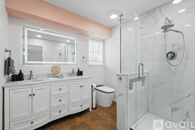 A bathroom with a marble shower and a white vanity.