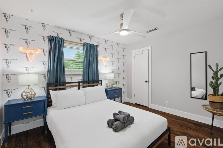 A bedroom with a white bed, blue nightstand, and a ceiling fan.