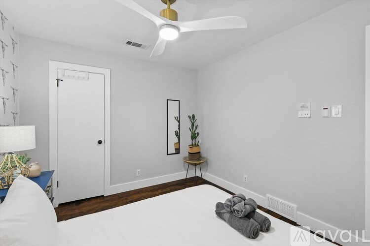 A room with a ceiling fan and a plant on a side table.