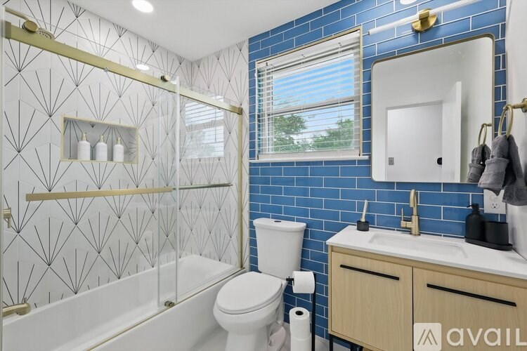 A bathroom with blue tiles and a white toilet.