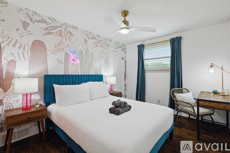 A bedroom with a white bed and a ceiling fan.