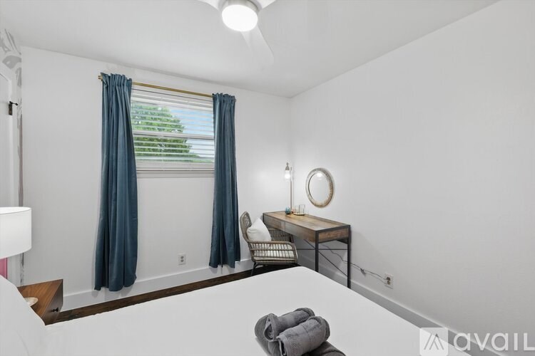 A room with a grey sofa, a round mirror, and a window with blue curtains.
