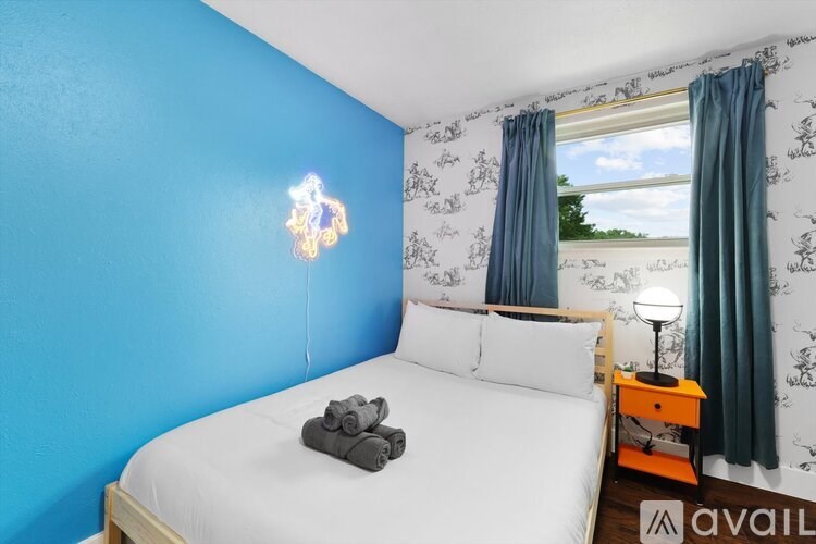 A bedroom with a blue wall and a bed with towels on it.