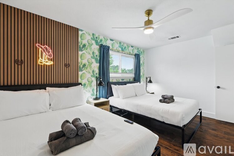 A room with two beds and a neon sign on the wall.