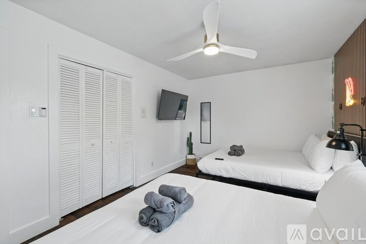 A bedroom with a bed, a ceiling fan, and a television.