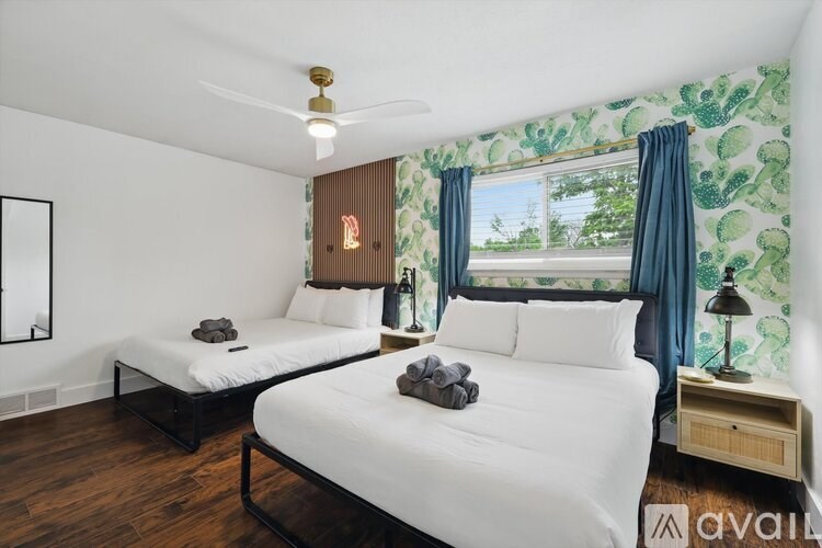 A bedroom with two beds, one of which is made, and a ceiling fan.