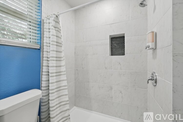 A bathroom with a white tub and a shower with a white curtain.