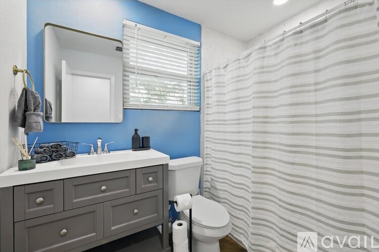 A bathroom with a white toilet, a sink with a mirror above it, and a shower with a striped shower curtain.