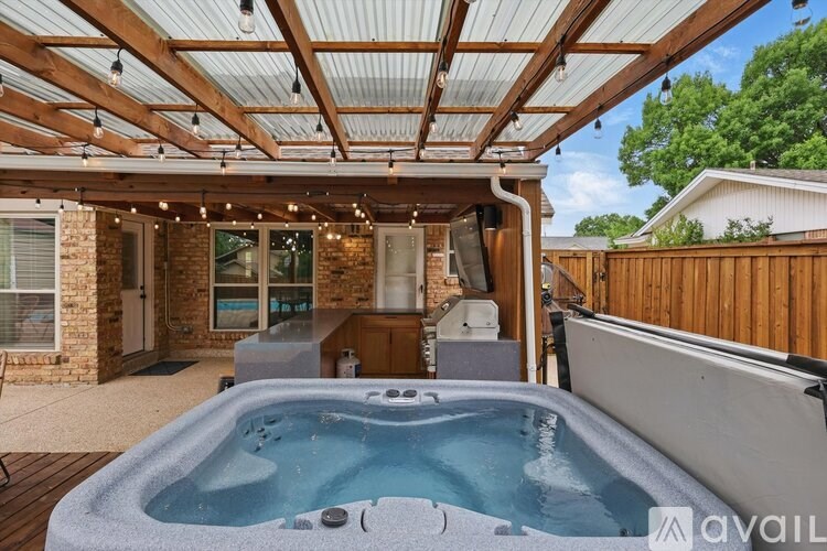 A hot tub is in the middle of a covered deck.