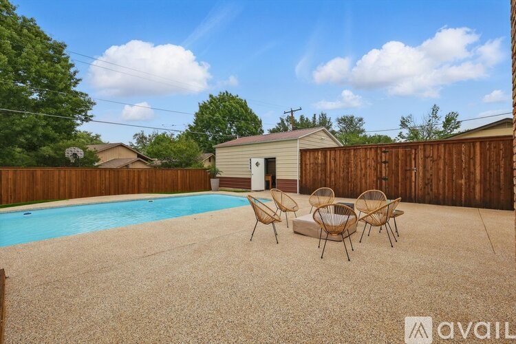 A backyard with a pool, patio furniture, and a wooden fence.