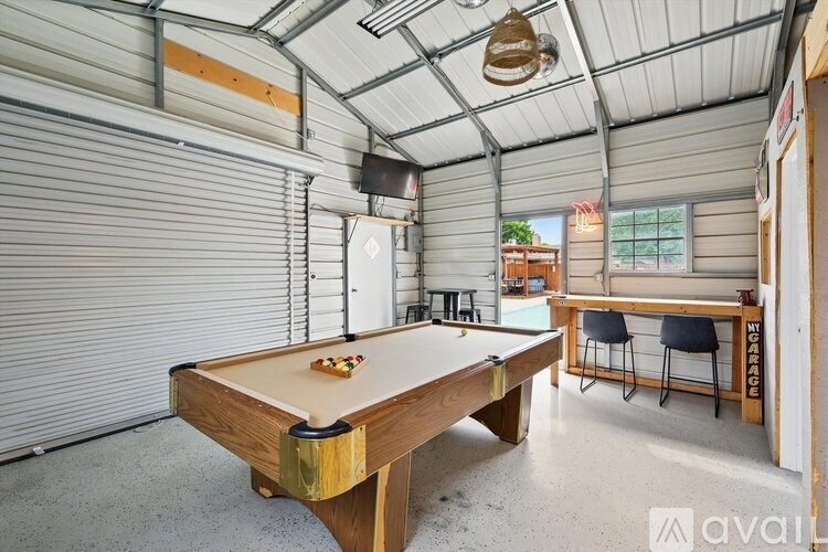 A pool table is in the middle of a room with a ping pong table and chairs.