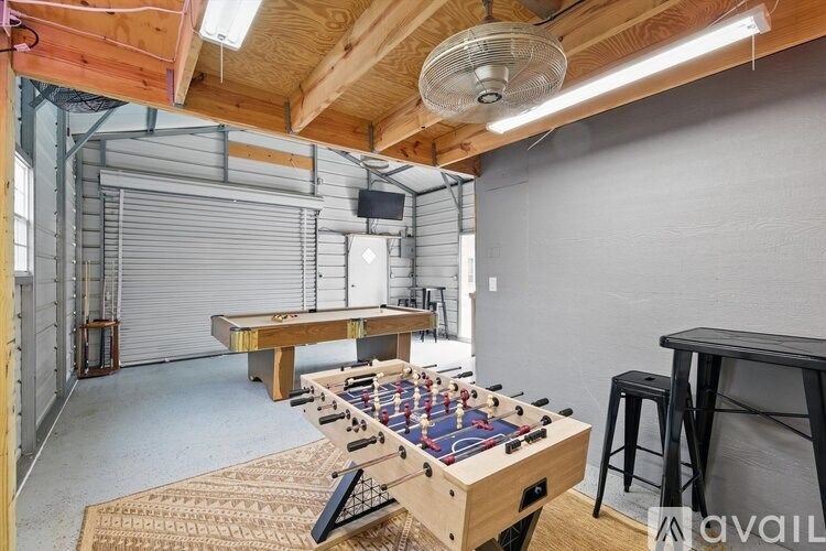 A foosball table is in the middle of a room with a bar stool and a table in the background.