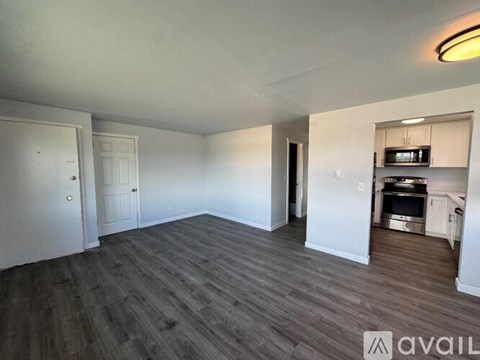 A spacious living area with a kitchenette and hardwood flooring.
