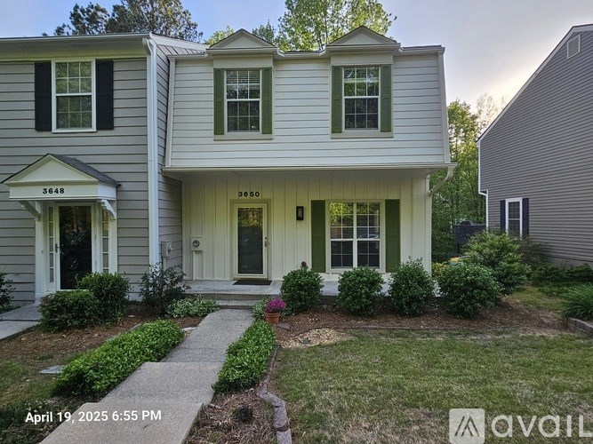 A two-story house with a front yard and a walkway leading to the front door.