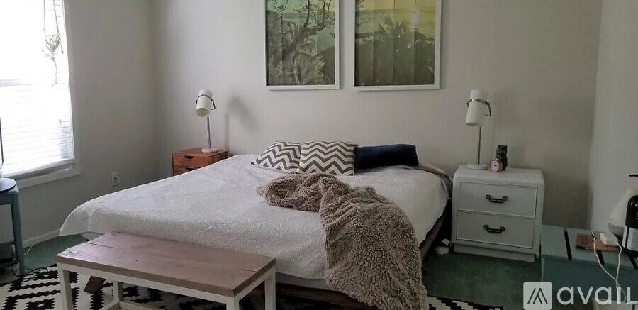 A bedroom with a bed, nightstand, and a painting on the wall.