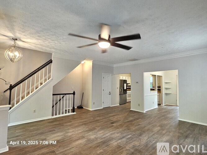 A spacious room with a staircase and a ceiling fan.