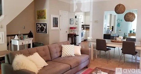 A living room with a brown couch and a white pillow.