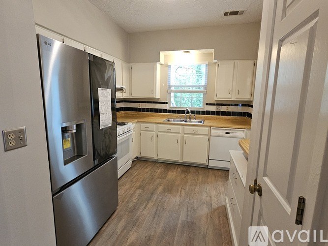 A kitchen with a stainless steel refrigerator and white cabinets.
