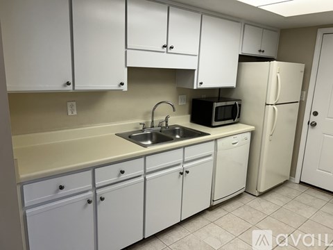 A kitchen with white cabinets and a white refrigerator.