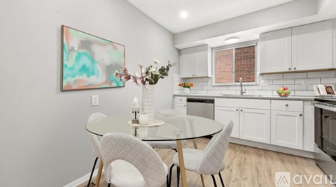 A modern kitchen with a glass table and white chairs.