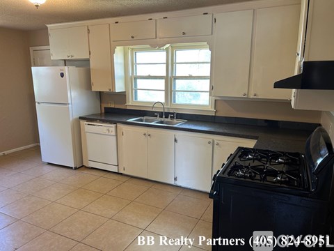 A kitchen with white cabinets and a black stove top.