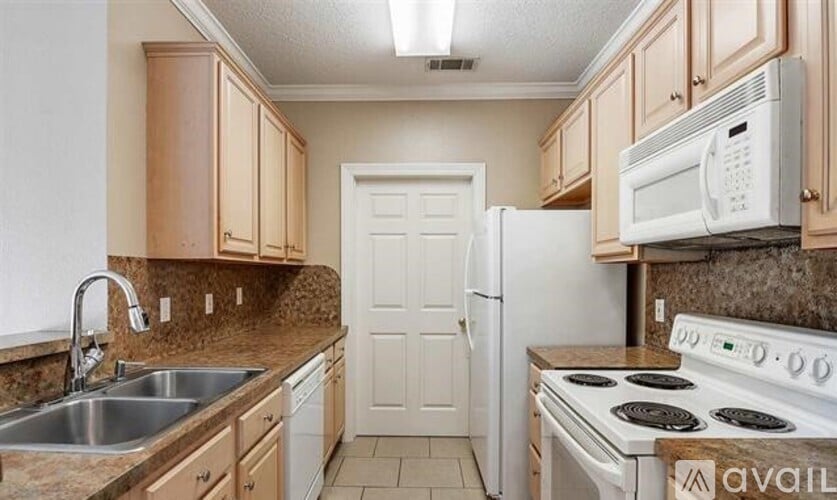 A kitchen with a white stove, sink, and cabinets.